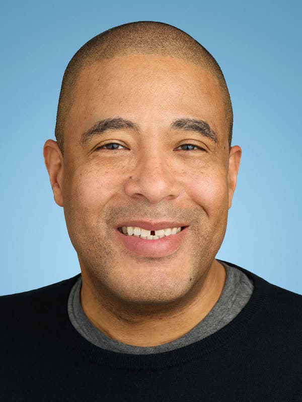 Sam Wilson headshot Portrait of Sam Wilson, creative director, against a blue background